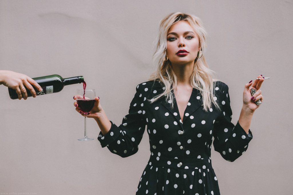 Woman drinking wine and smoking a cigarette | Say "Hello" to a Healthy Heart: Three Effortlessly Cool Ways to Keep Your Ticker in Check | Concierge Health and Aesthetics | Sarasota, Florida